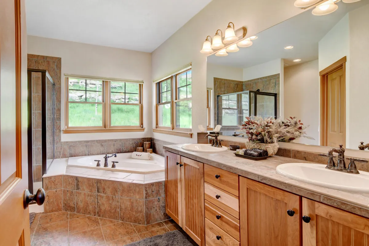 A serene, spa-inspired bathroom with a luxurious bathtub, double sink vanity, large mirrors, and abundant natural light streaming in from the windows. The mood is tranquil and soothing.