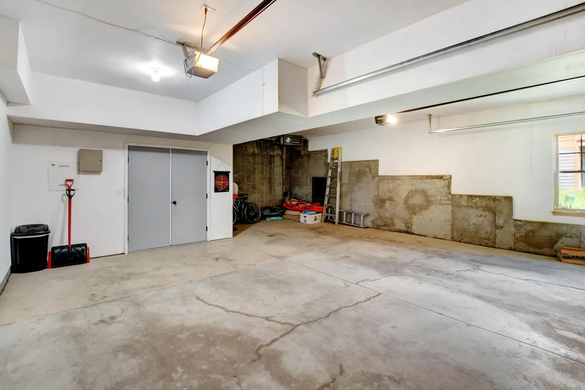 A practical, well-organized garage interior displays parked bicycles, ladders, and a sturdy concrete floor, suggesting ample space for bike storage and adventure gear. The storage area reflects readiness for both winter and summer activities.