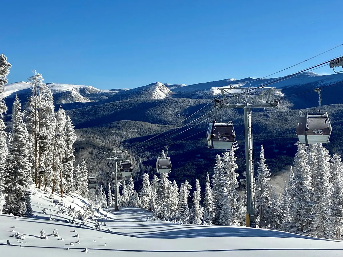A sweeping view of snowy mountains with gondola lifts ascending over snow-covered trees, capturing the dynamic energy of a ski resort. The image conveys a sense of adventure and the thrill of winter sports, with scenic vistas and the promise of exciting downhill runs.